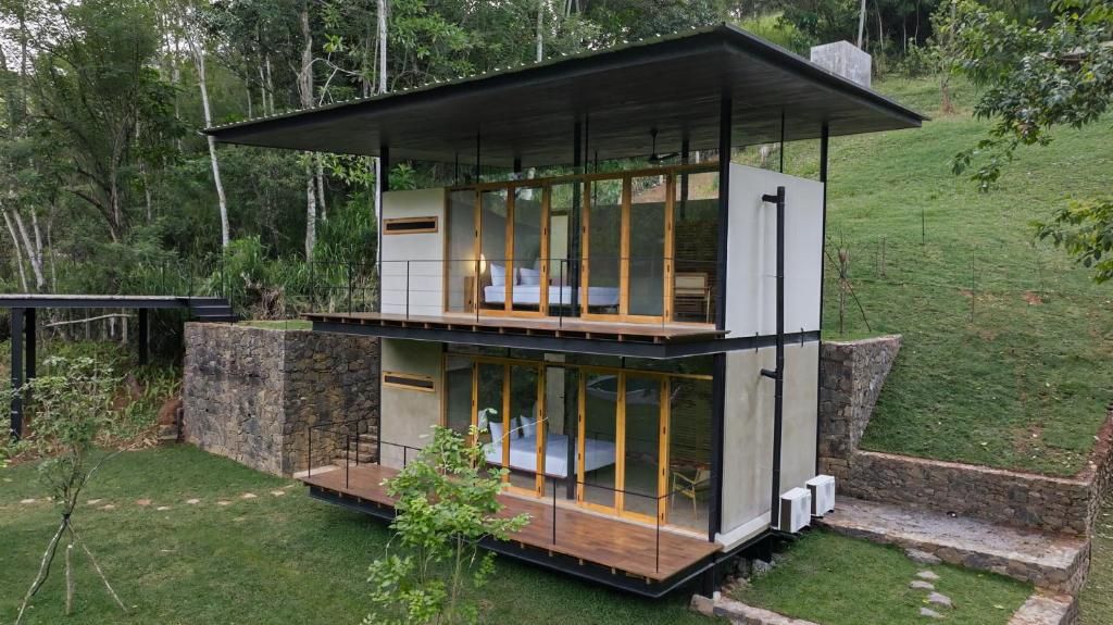 Una casa moderna de dos pisos con amplios ventanales, techo plano y base de piedra.