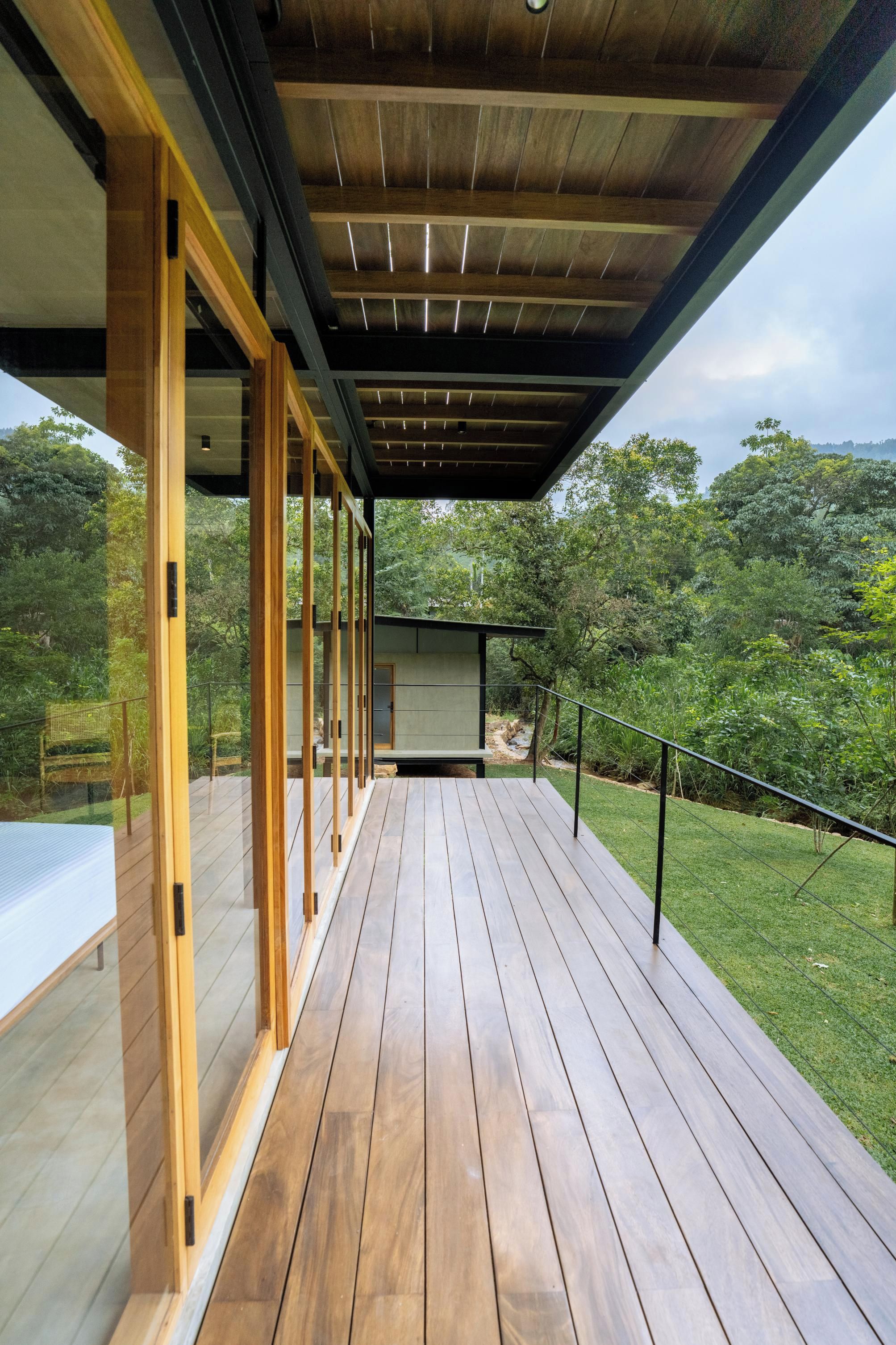 A wooden deck with a glass enclosure, overlooking a lush green landscape.