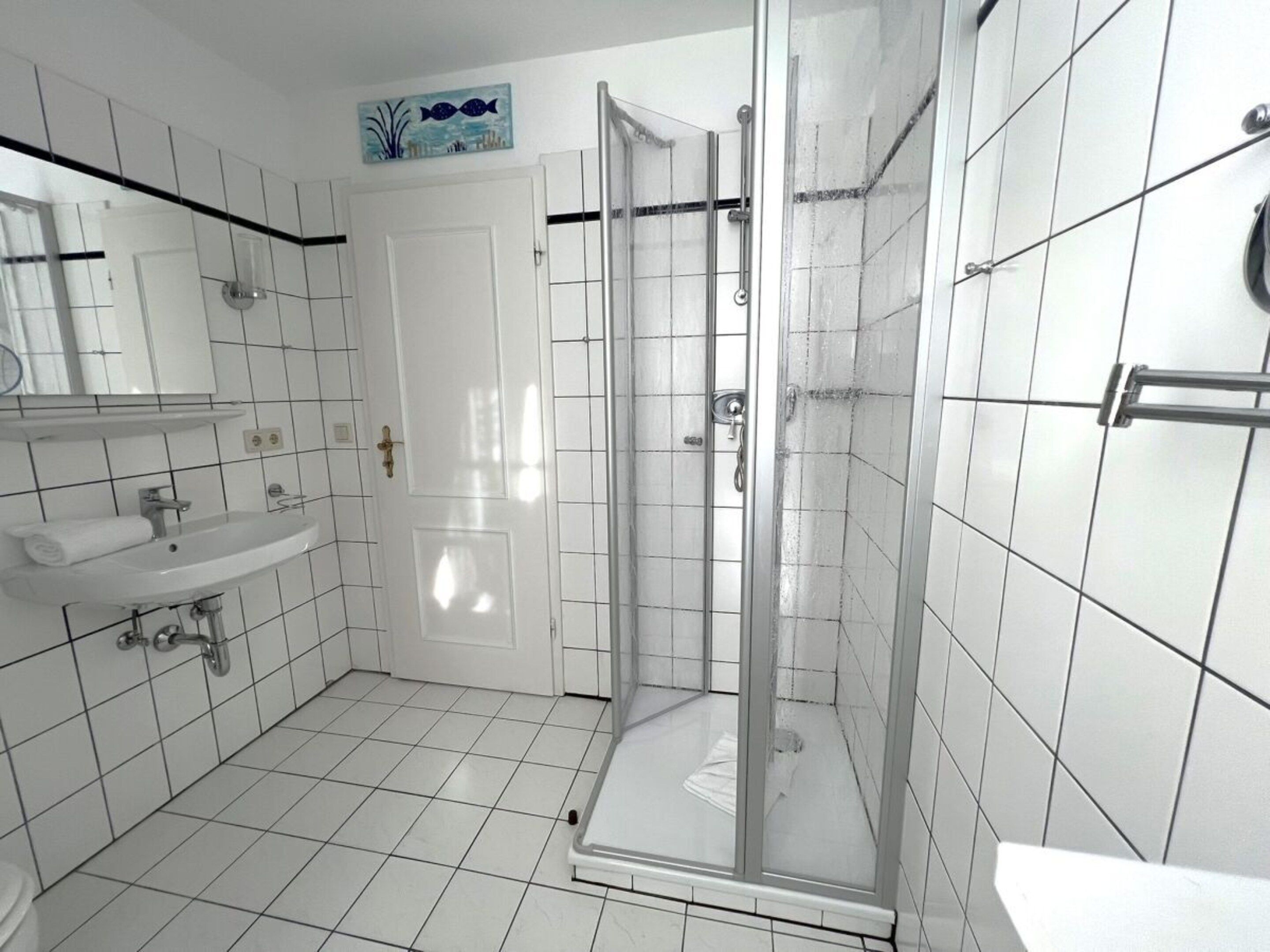 A bathroom with a glass-enclosed shower, a sink, and a mirror.