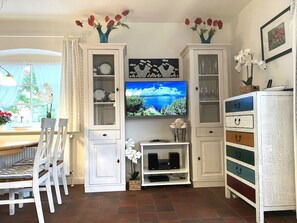 A dining area with a table and chairs, a television mounted on the wall, and cabinets with decorative items. - Holiday Home in Wrixum With Terrace (Wrixum)