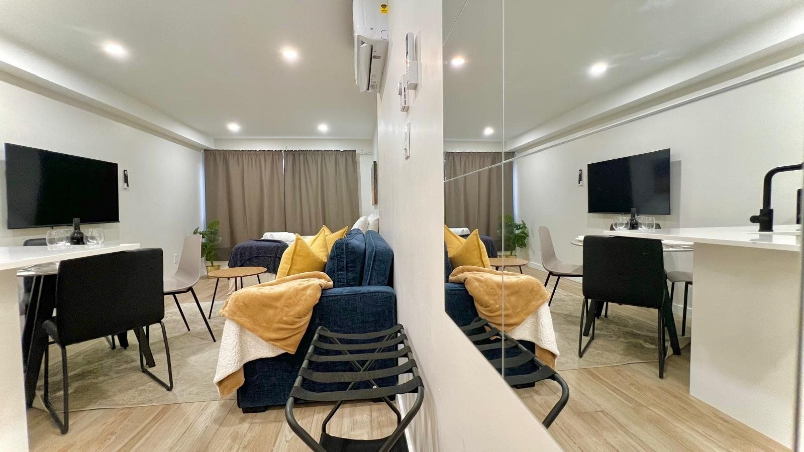Una habitación de hotel moderna con sofá, sillas, escritorio y televisor.