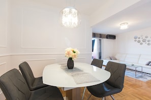 Un espace repas moderne avec une table ronde, des chaises noires, un vase de fleurs et des luminaires suspendus.