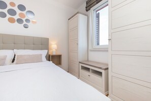 A bedroom with a bed, bedside table, wardrobe, and a window. - Apartment Parentium - Stay in the heart of Porec (Poreč)