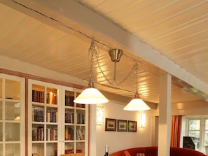Ein Zimmer mit einem Bücherregal, einem roten Sofa und einer Pendelleuchte.