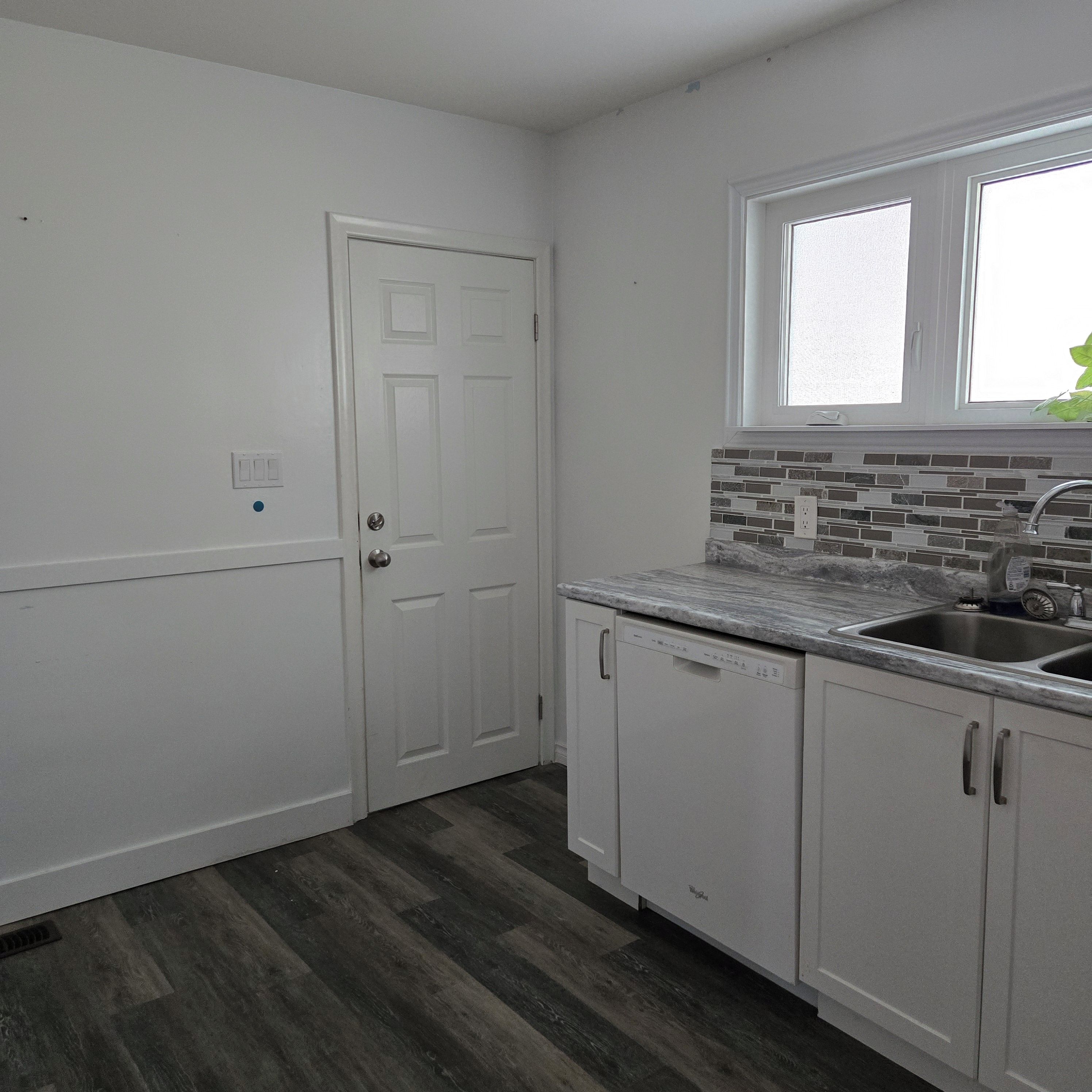 A kitchen with white cabinetry, a built-in dishwasher, a granite countertop, and a window above the sink.