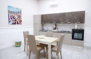 A modern kitchen with marble cabinets, a dining table with chairs, and a painting on the wall. - Casillo House Vacation Rental (Napoli)