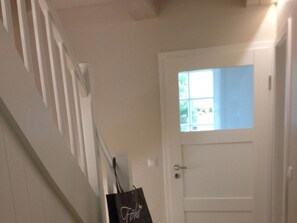 A white door with a window, a white wall, and a white staircase. - Holiday Home in Oldsum With Swimming Pool (Oldsum)