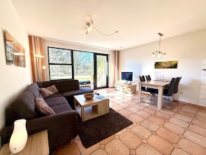 A modern living room with a sofa, coffee table, and dining area. - Holiday Apartment in Wyk on Fohr With Sauna (Wyk auf Foehr)