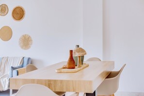 Een minimalistische eethoek met een houten tafel, stoelen en een decoratieve vaas.