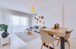 A modern living room with a dining area, featuring a sofa, a coffee table, and a dining table with chairs. - Brisa Algarvia 2: A Cozy Apartment in Faro (Faro)