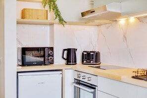 Een kleine keuken met een magnetron, koffiezetapparaat en oven.