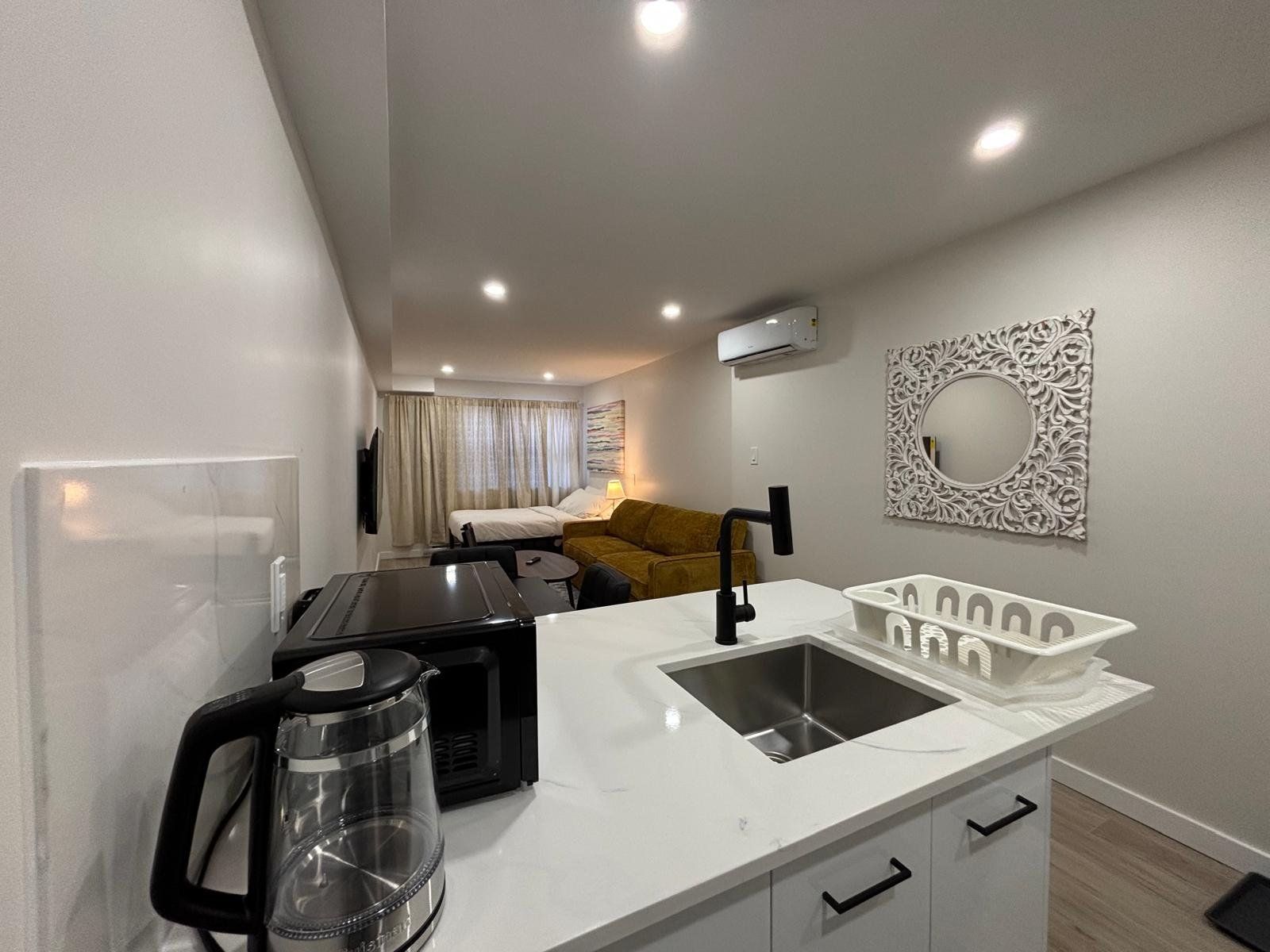 Una kitchenette compacta con cafetera, lavamanos y microondas.