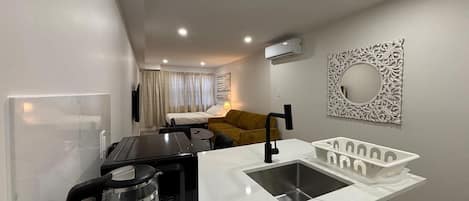 A compact kitchenette with a coffee maker, a sink, and a microwave.