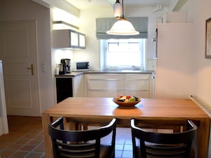 A compact kitchen with a dining table, two chairs, a bowl of fruit, and a coffee maker. - Holiday Apartment With 1 Bedroom (Borgsum)