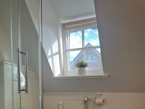 A bathroom with a skylight, a radiator, and a window with a plant. - Holiday Apartment With 1 Bedroom (Borgsum)