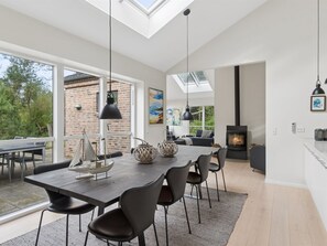 A modern dining area with a large table, chairs, pendant lights, and a view of the outdoors. - "Evtim" - 275m from the sea by Interhome (Højby)