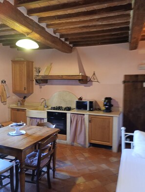 Cozinha com armários de madeira, mesa de jantar e micro-ondas.