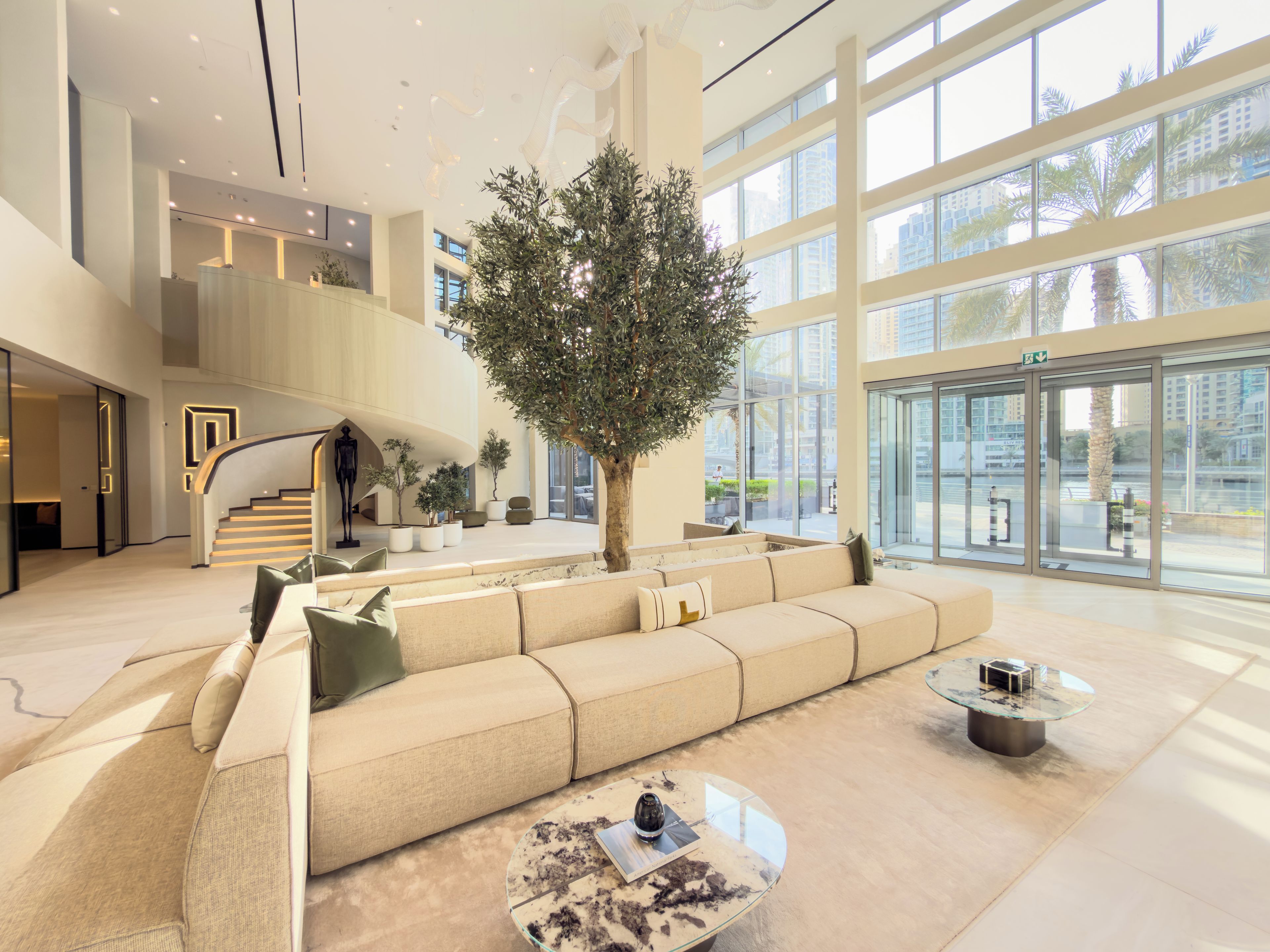 A modern lobby with a large sofa, a coffee table, and a staircase leading to an upper level.