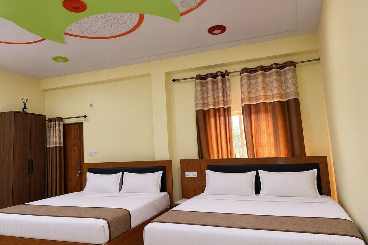 A hotel room with two beds, a wardrobe, and a ceiling with decorative elements.