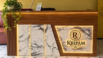 A reception desk with a marble design, a logo, and a QR code for Kripam.