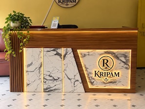 A reception desk with a marble design, a logo, and a QR code for Kripam. - HOTEL RADHE SHYAM KRIPAM (Mathura)