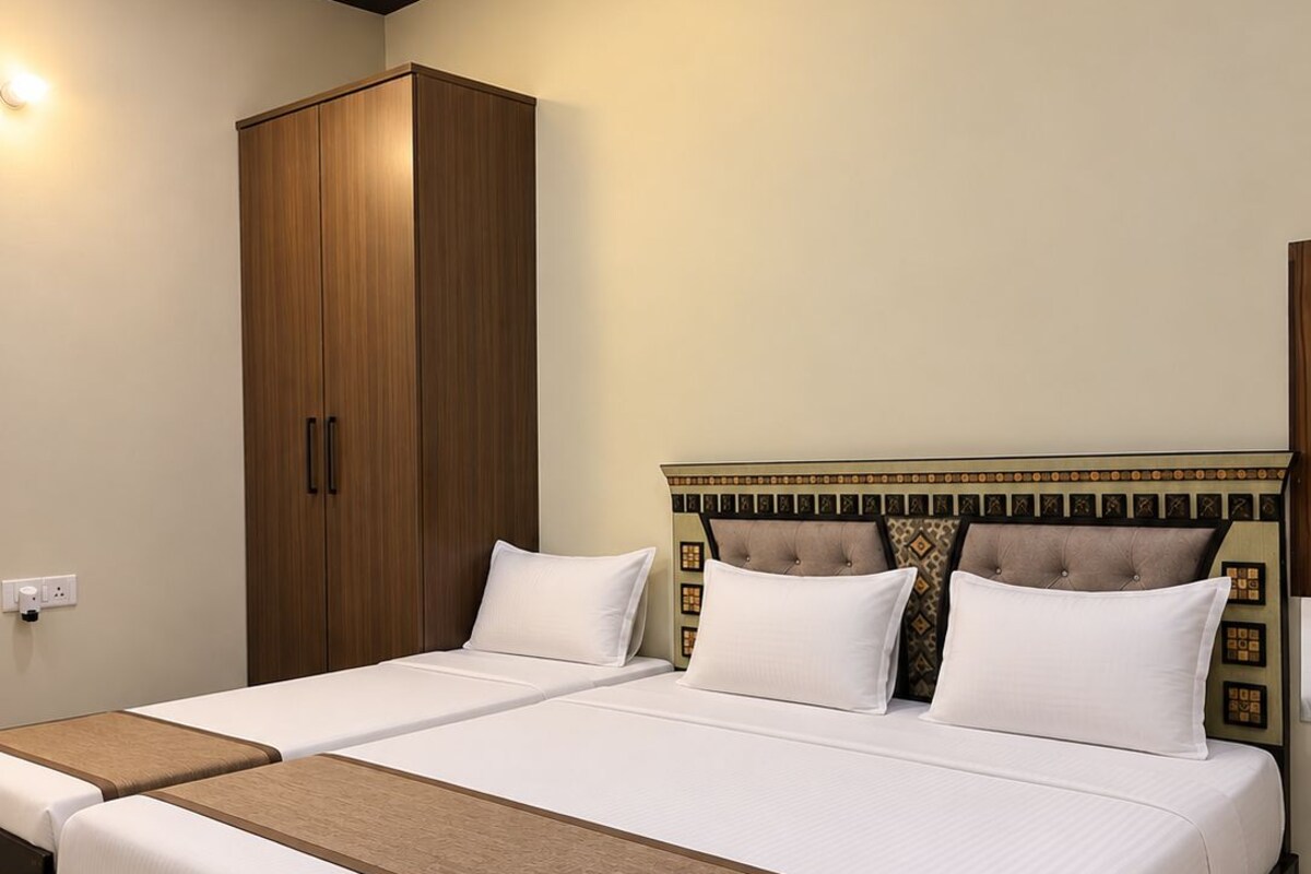 A hotel room with a large bed, a wardrobe, and a wall-mounted control panel.