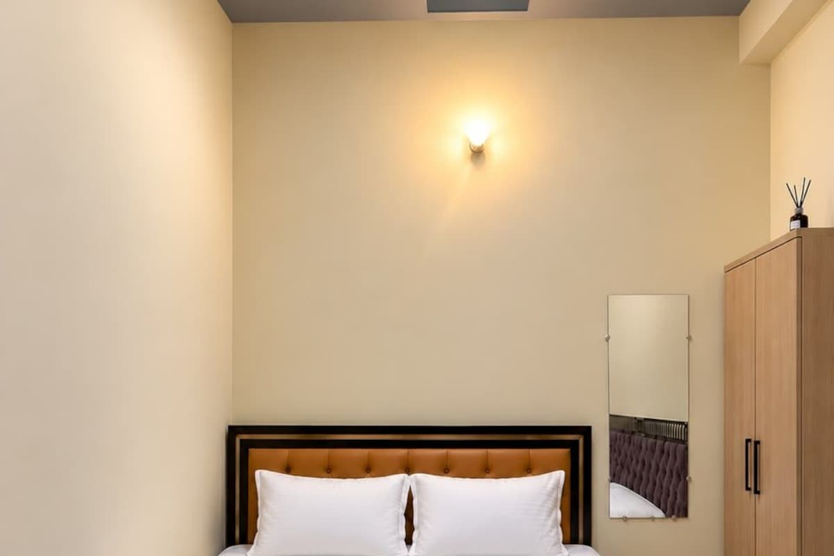 A hotel room with a large bed, a wardrobe, and a wall-mounted light fixture.