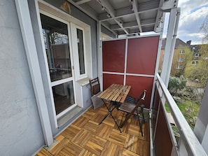 Ein Balkon mit Holzboden, einem Tisch und Stühlen.