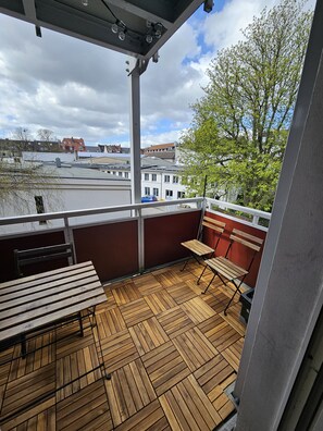 A balcony with wooden flooring, metal railings, and a view of buildings and trees. - Cozy apartment in the heart of Essen's Rüttenscheid neighborhood (Essen)