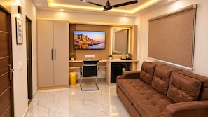 A modern living room with a sofa, a television, and a ceiling fan. - Hotel Vaishnavi Grand 200 m 80 Ghat (Varanasi)