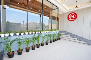 A reception area with a Nestlay logo, potted plants, and a staircase. - Nestlay Suites Tirupati (Renigunta)