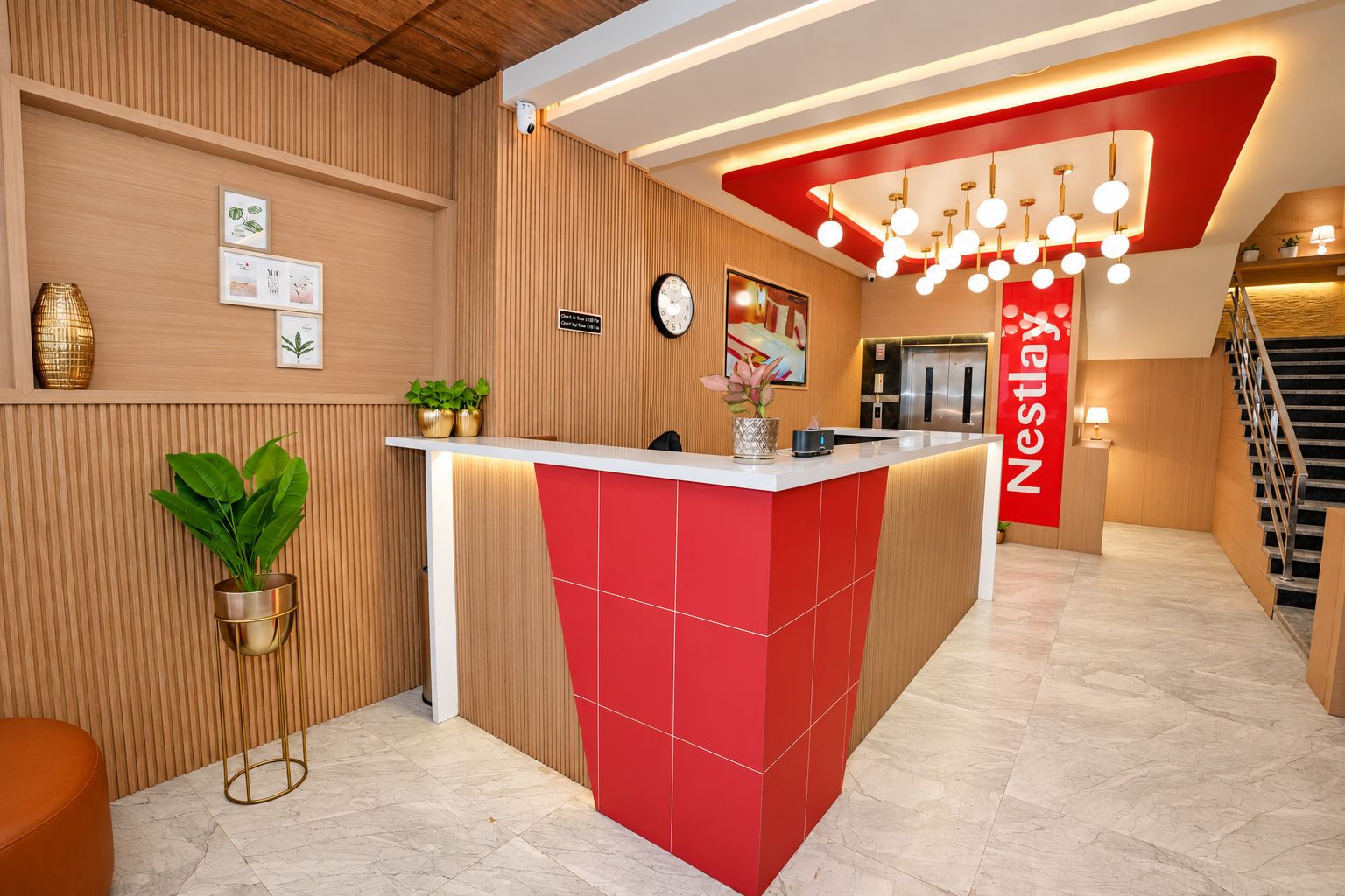 Una hall d'hotel dal design moderno, con una reception rosso e bianco, un orologio e una scala.