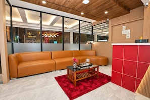 A modern living room with a leather sofa, a wooden coffee table, and a red rug.