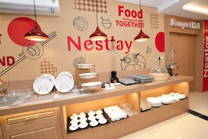 A Nestay branded food station with a variety of dishes and utensils, including plates, bowls, and glasses.