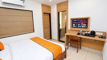 Ein Hotelzimmer mit Bett, Schreibtisch, Stuhl, Fernseher und Klimaanlage.