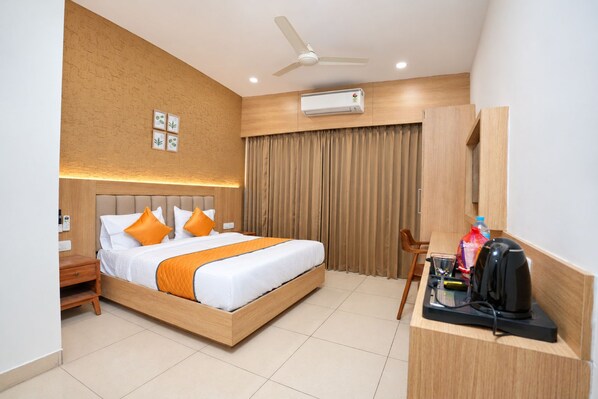 A hotel room with a bed, a desk, a chair, a ceiling fan, and an air conditioning unit.