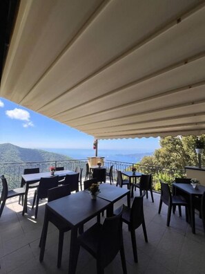 Une terrasse extérieure avec des tables et des chaises, une vue sur les montagnes et un espace abrité.