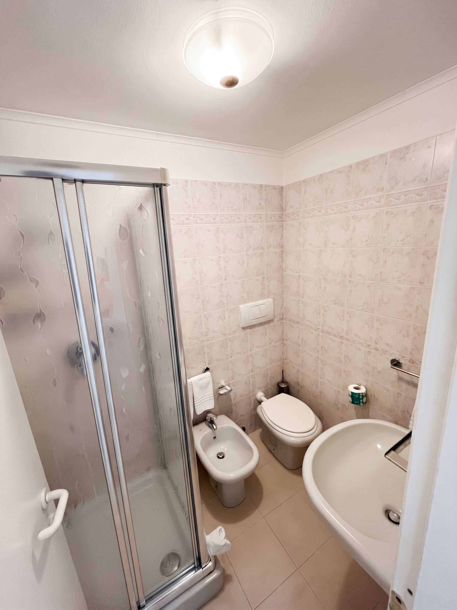 Un bagno con box doccia in vetro, un bidet, un WC e una vasca da bagno.