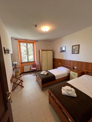 Une chambre d’h ôtel avec deux lits, un bureau, une chaise et une fenêtre.