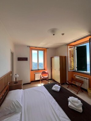 Une chambre d’hôtel avec un lit, une chaise, un bureau et une fenêtre donnant sur un paysage agréable.