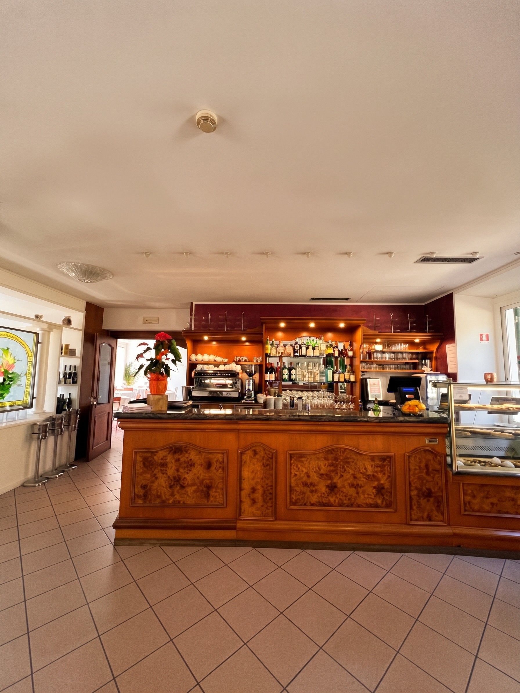 Una zona de bar con mostrador, estanterías llenas de botellas y una máquina de café.