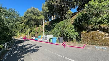 A road with a curve, trees, and parked vehicles.