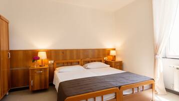 Une chambre d’hôtel avec un lit double, une tête de lit en bois, des tables de chevet avec des lampes, une armoire et un radiateur.