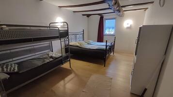Ein Zimmer mit Etagenbetten, einem Einzelbett, einem Kühlschrank und einem Fenster mit Vorhängen.