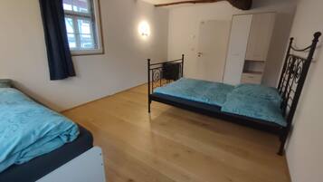 Une chambre avec deux lits, une armoire, une petite table et une fenêtre avec des rideaux.
