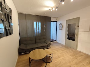 Ein modernes Wohnzimmer mit einer Couch, einem runden Holztisch und einer Wanduhr.