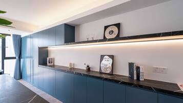 Una cucina moderna con mobili blu scuro, un piano di lavoro in marmo e un orologio a parete.