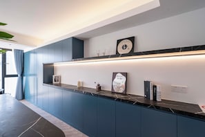A modern kitchen with dark blue cabinets, a marble countertop, and a wall-mounted clock. - Book&Bed-The Bund People's Square 3 (Huangpu District)
