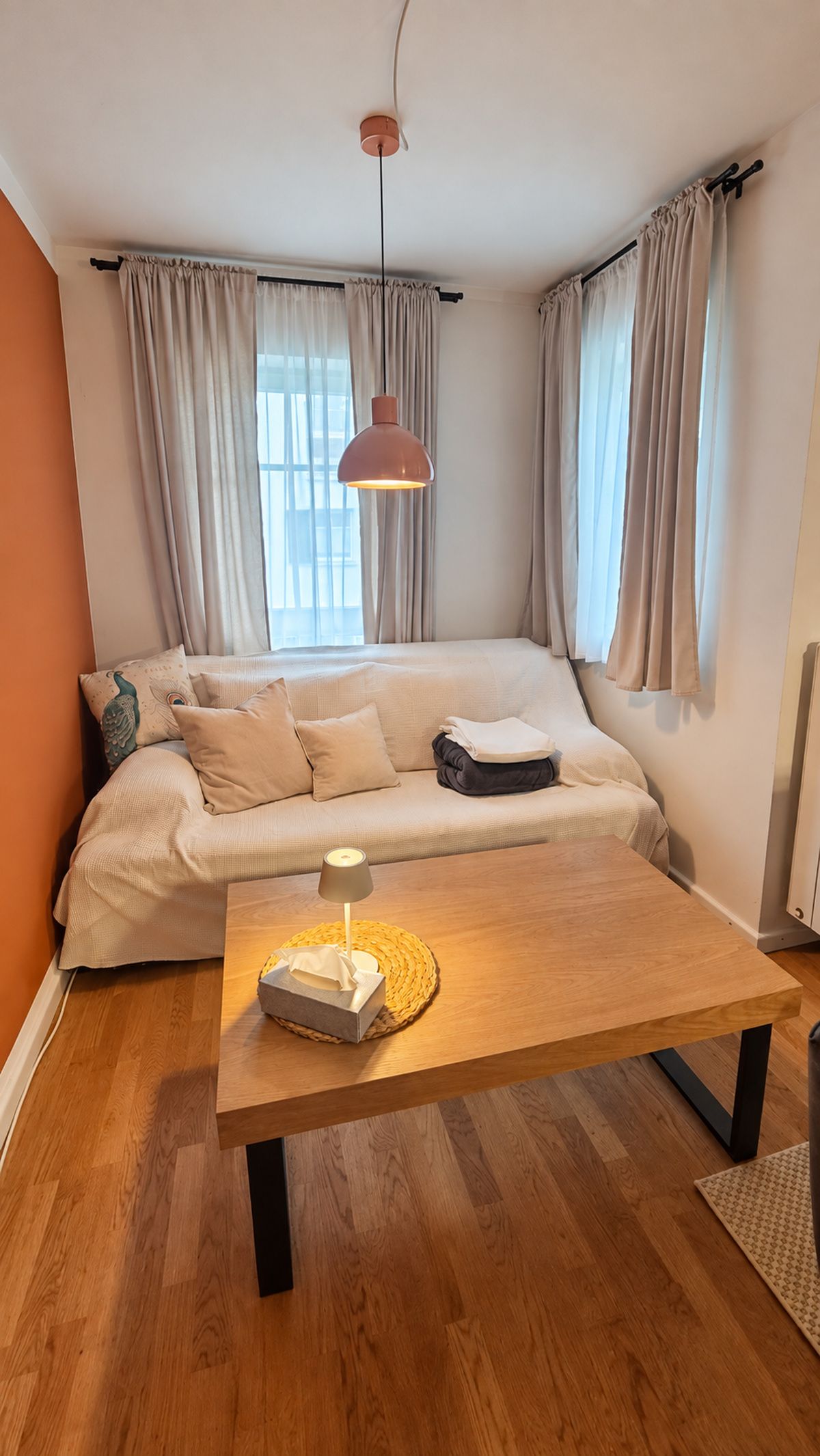 Una habitación acogedora con un sofá, una mesa de madera y una lámpara colgante.