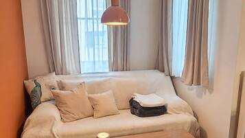 Una habitación acogedora con un sofá, una mesa de madera y una lámpara colgante.
